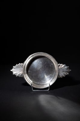 an antique silver plate with a leaf decoration on a black background
