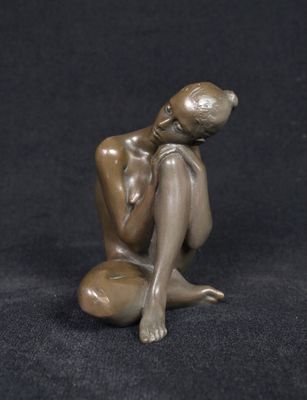 statue of a woman sitting on a rock on a black background