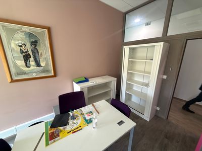 a white table with purple chairs and a painting on the wall