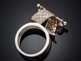 a close up of a silver ring with a diamond and a garnett