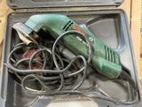 a green electric drill in a black case on a table