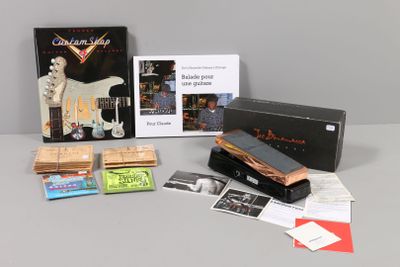 une photo d'une collection d'objets liés à la musique, comprenant notamment une guitare, une cassette, un CD et d'autres objets