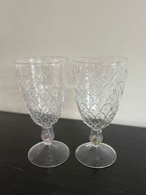 pair of crystal goblets on black table with white wall in background