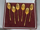 six gold spoons in a box with a red velvet lining