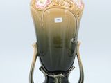 a vase that is sitting on a stand on a white surface