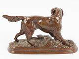 bronze statue of a dog standing on a rock on a white background