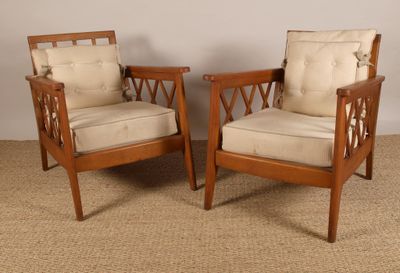 une paire de chaises de style « mid-century » avec des coussins beiges, posées sur un sol recouvert de moquette