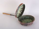 a small metal pan with a wooden handle on a white surface