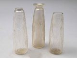 trois vases en verre posés l'un à côté de l'autre sur une table