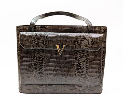 un gros plan sur un sac à main en cuir de crocodile marron orné d'un « V » doré sur la poignée