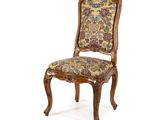 une image d'une chaise en bois dont l'assise est recouverte d'un rembourrage floral