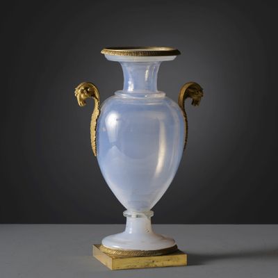 un vase en verre muni d'une poignée dorée, posé sur une table