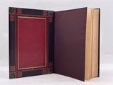 an open book with a red cover sitting on top of a white surface