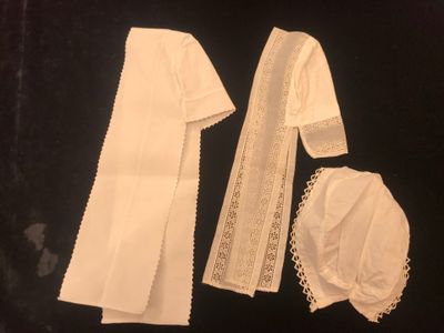 an image of a white dress and bonnet are on a black surface
