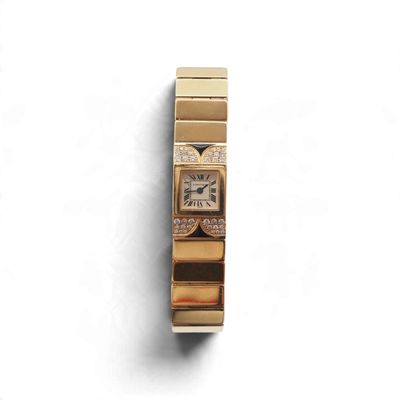une montre en or sertie de diamants, posée sur un fond blanc