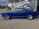une photo d'une Mustang bleue garée devant un garage rétro