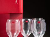 three empty wine glasses in front of a red box with a red ribbon