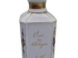 a white bottle with a gold top and a flower design