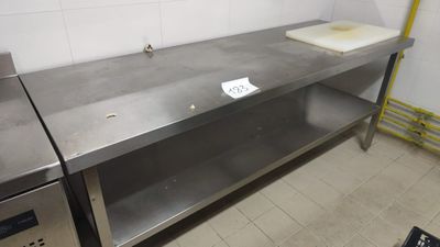 a stainless steel table with a cutting board on top of it