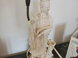 une statue représentant une femme tenant une bougie posée sur une table