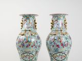 pair of chinese vases with figures on them sitting on a white surface