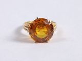 a close up of a ring with an orange stone in it