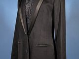 black tuxedo suit on mannequin stand against blue background