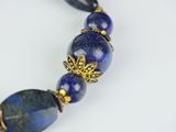 a close up of a necklace with blue beads on a white surface