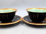pair of black and gold coffee cups and saucers with numbers on them
