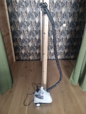 a steam iron sitting on a wooden floor in front of a curtain