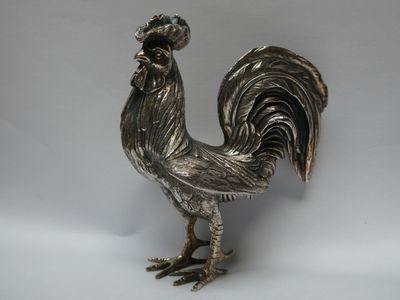 un coq argenté posé sur une surface blanche
