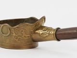 an old brass teapot with a wooden handle on a white background