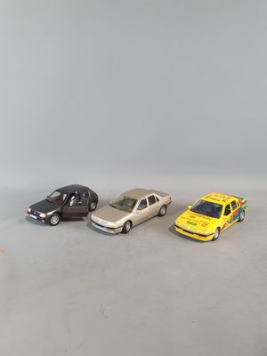 three toy cars are lined up in a row on a white surface