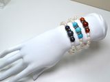 une main de mannequin blanche tenant un bracelet orné de perles multicolores