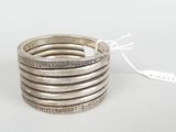a close up of a stack of five silver rings on a white surface