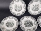 four plates with black and white designs on them on a black surface