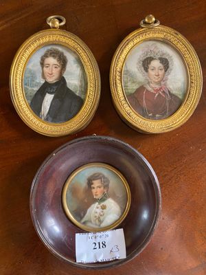 two miniature portraits of a man and a woman on a table