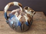 a brown and blue vase sitting on a wooden table