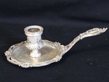 a silver candle holder with a spoon on top of it