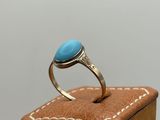 une image représentant une bague ornée d'une pierre turquoise posée sur une boîte en bois
