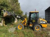 a backhoe of a construction vehicle that is parked in the grass