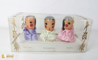 trois petites figurines dans une boîte transparente posée sur une surface blanche