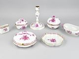 Plusieurs pièces de porcelaine rose et blanche sont disposées sur une surface grise