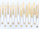 many forks and knives that are lined up on the table