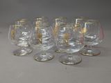 six verres à vin à bord doré sont alignés sur une table