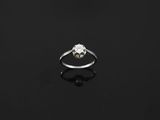 a single stone diamond ring on a black surface