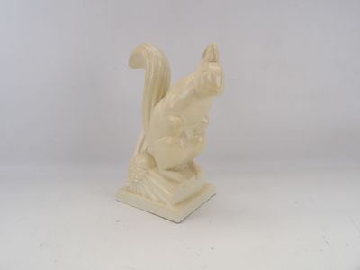 cream colored sculpture of a squirrel on a rock