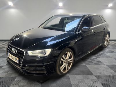 Une Audi noire est garée sur un sol en damier dans un garage.