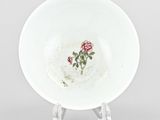 a white plate with a rose on it on a stand