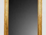 un miroir à cadre doré posé sur un mur blanc